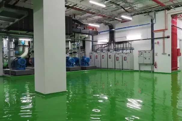 Standing water reflects equipment and columns inside an industrial building