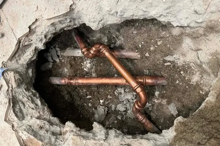 Copper supply pipes exposed through an opening in a concrete floor